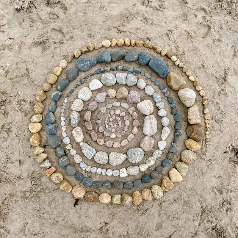 Smooth stones laid in rings on the sand, spiraling into a small circle at the center