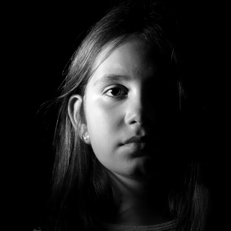 A young girl in black and white, half her face in shadow